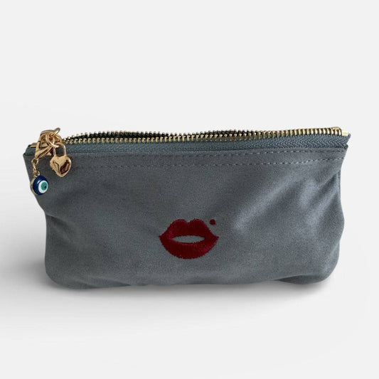 Evil eye charm clipped onto grey Pout Pouch makeup bag