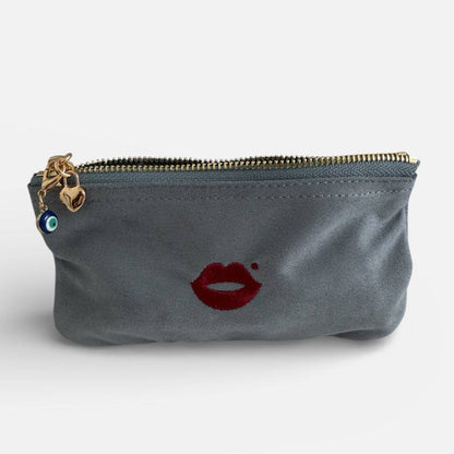 Evil eye charm clipped onto grey Pout Pouch makeup bag